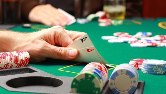 "Poker players sitting around a table, focusing on their cards and chips during a cash game."